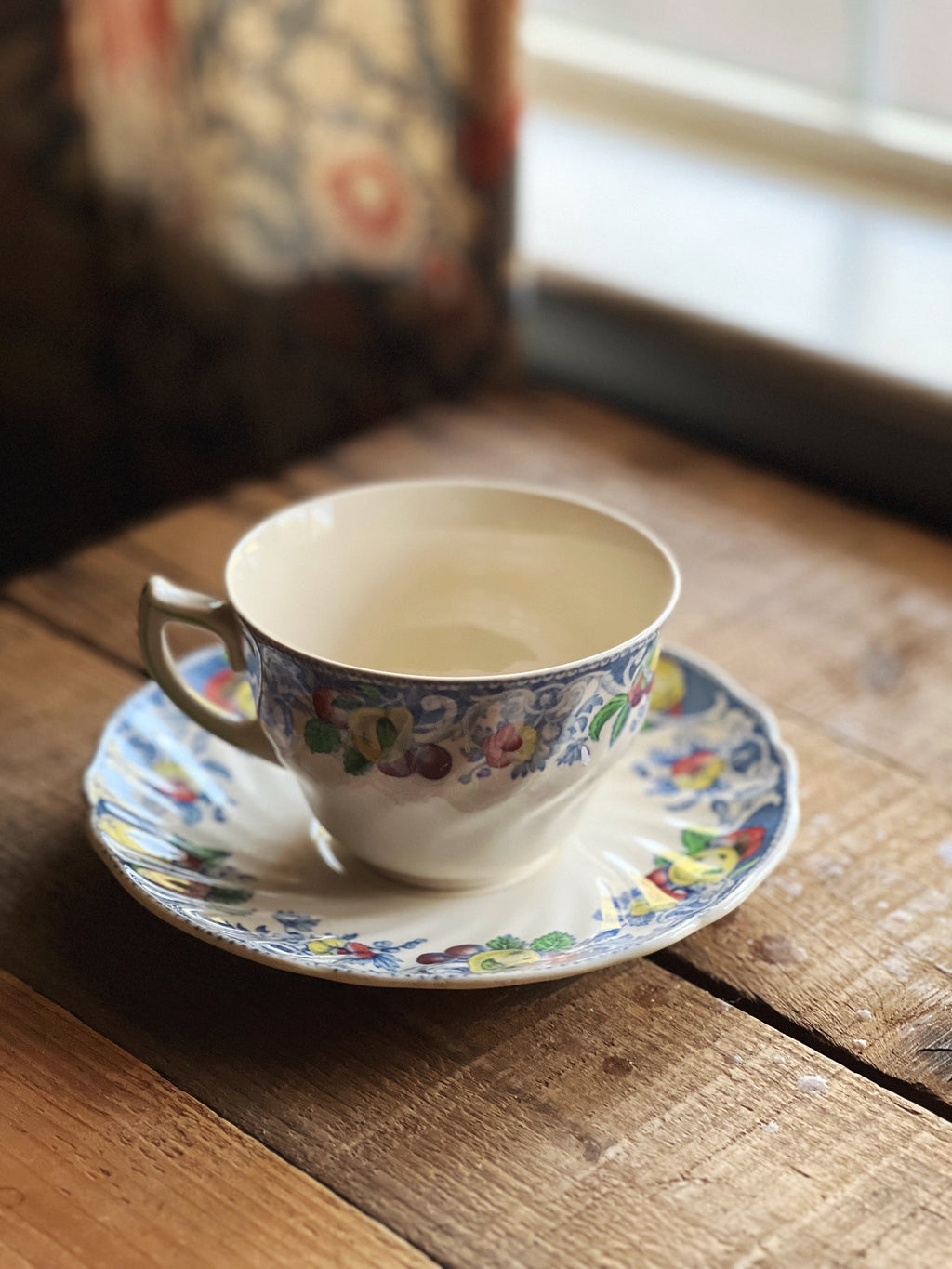 Teacup and saucer with floral design on a wooden surface