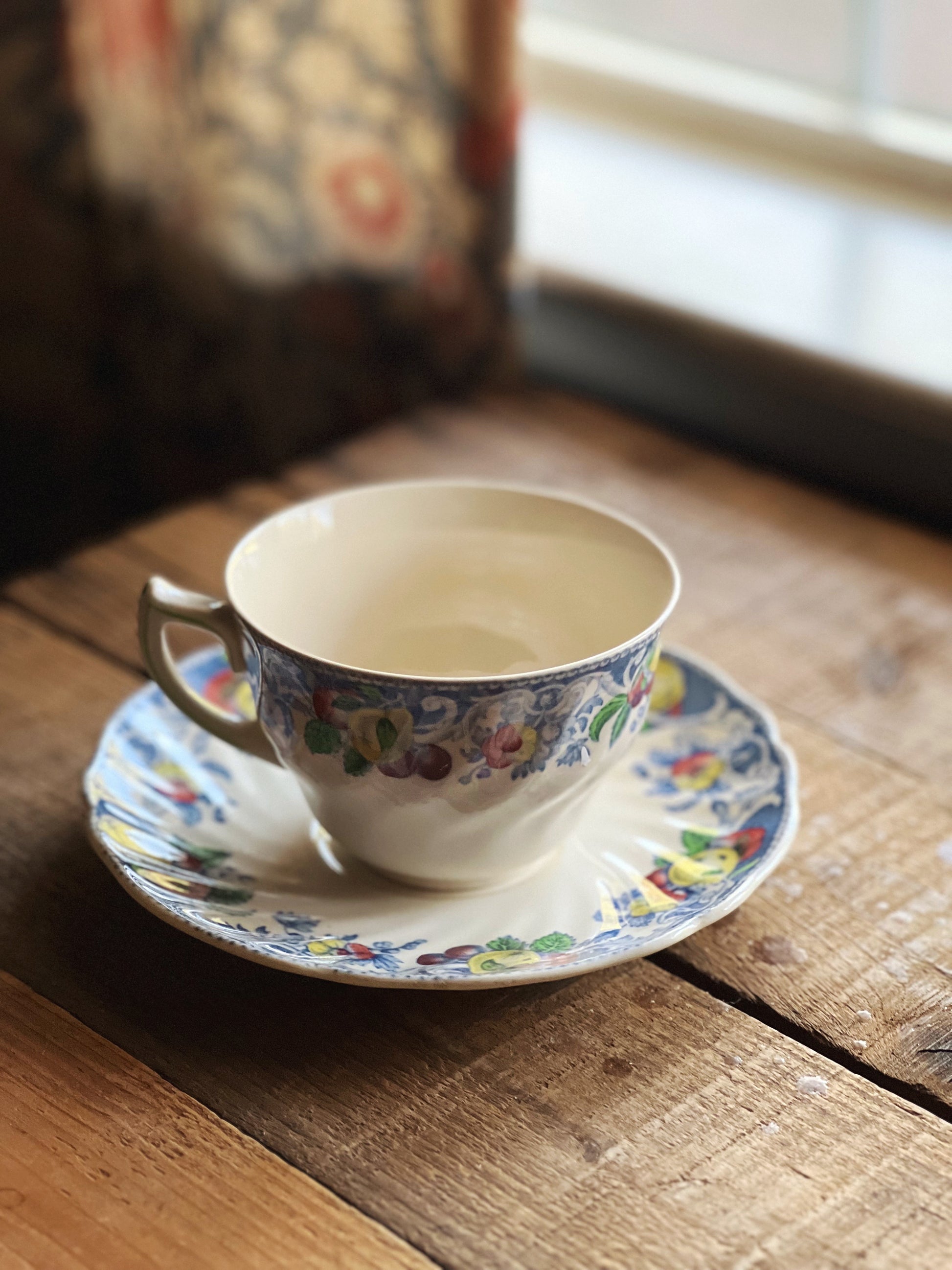 Teacup and saucer with floral design on a wooden surface