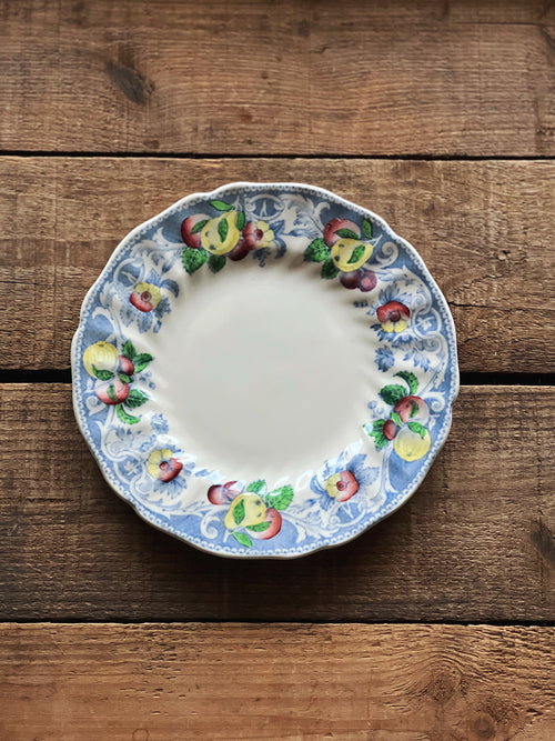 Decorative ceramic plate with fruit design on a wooden surface