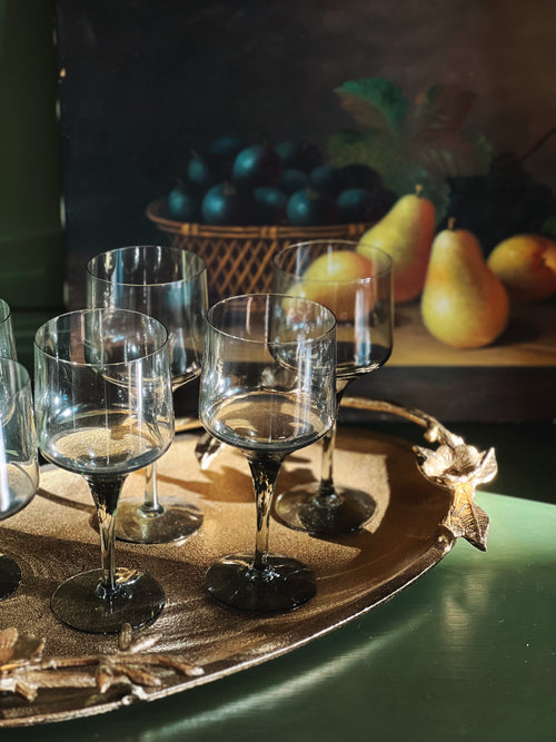 Wine glasses on a decorative tray with pears in the background