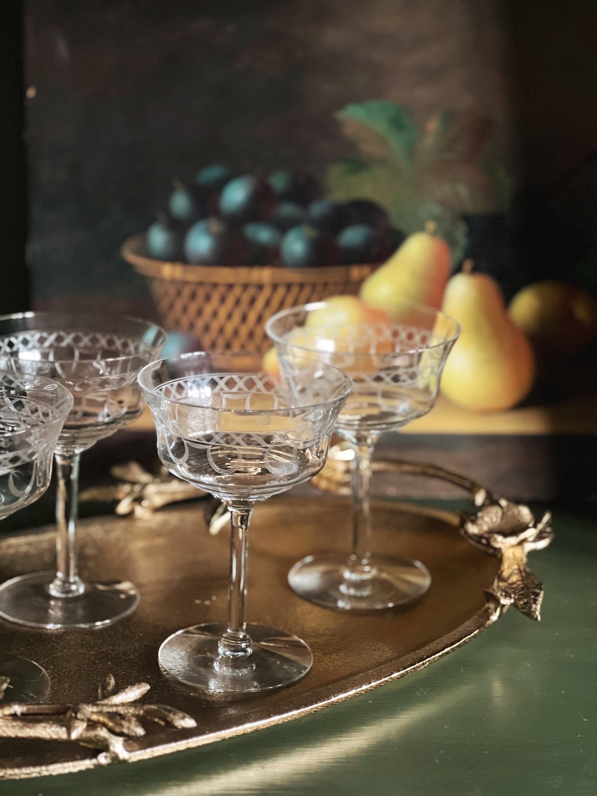 Clear glass goblets on a decorative tray with fruit in the background