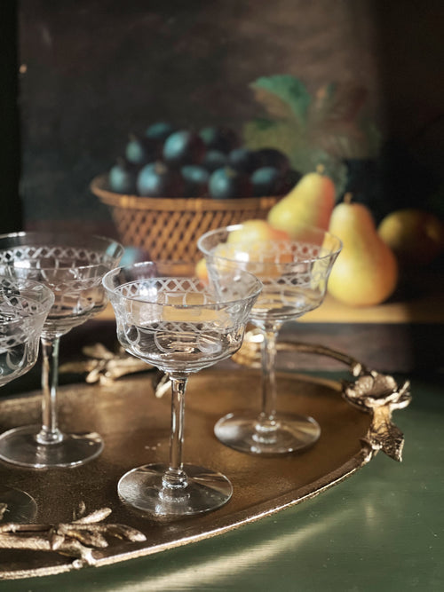 Clear glass goblets on a decorative tray with fruit in the background