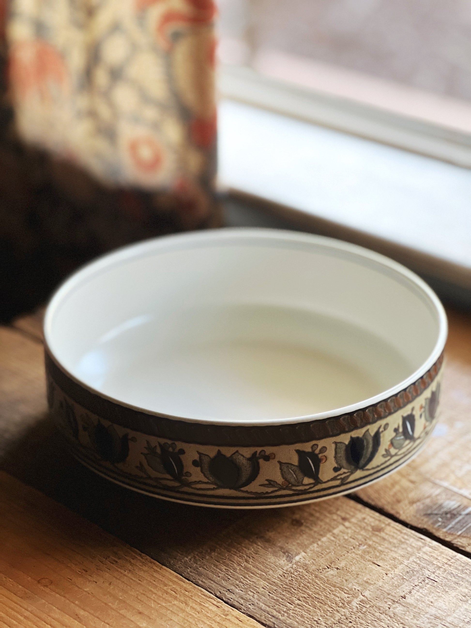 Ceramic bowl with decorative rim on a wooden surface