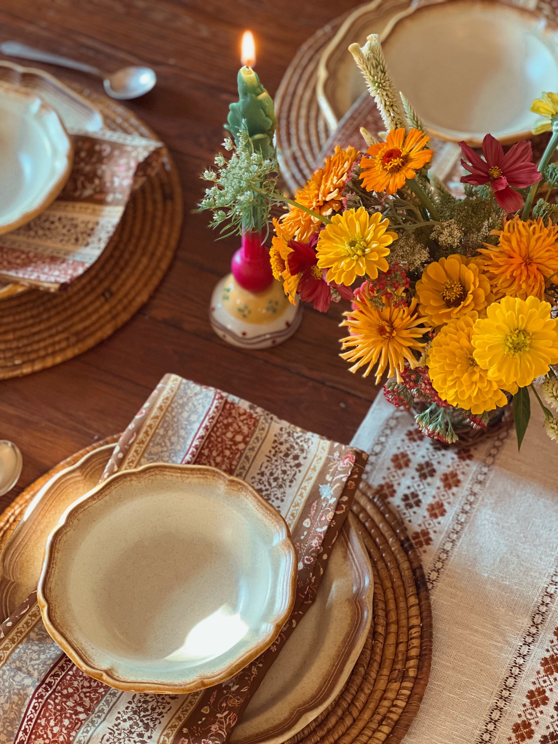 Decorative table setting with flowers, candles, and patterned tableware.