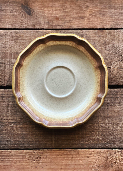 Ceramic saucer with brown rim on a wooden surface
