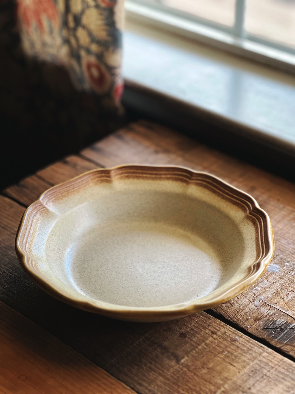 Ceramic soup bowl on a wooden surface with a window in the background