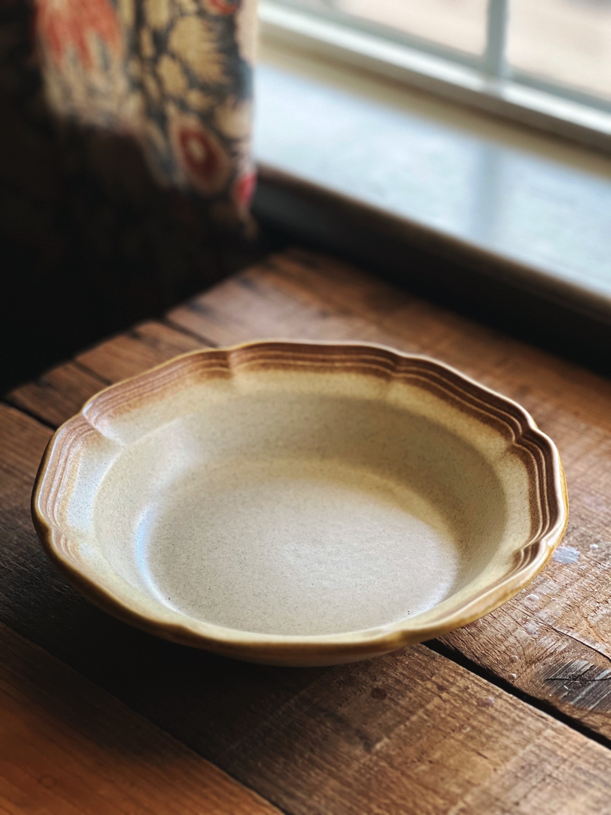 Ceramic soup bowl on a wooden surface with a window in the background
