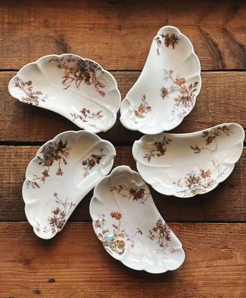 Five white ceramic dishes with floral patterns on a wooden surface