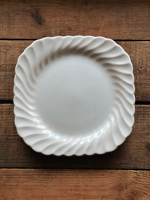 White ceramic plate with decorative edge on a wooden surface