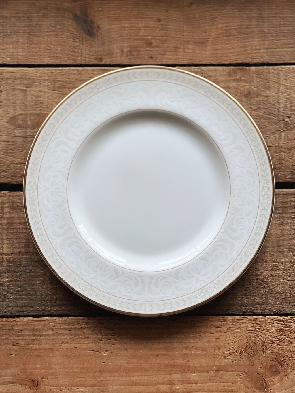 White plate with decorative rim on a wooden surface