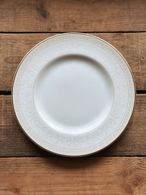White plate with decorative rim on a wooden surface