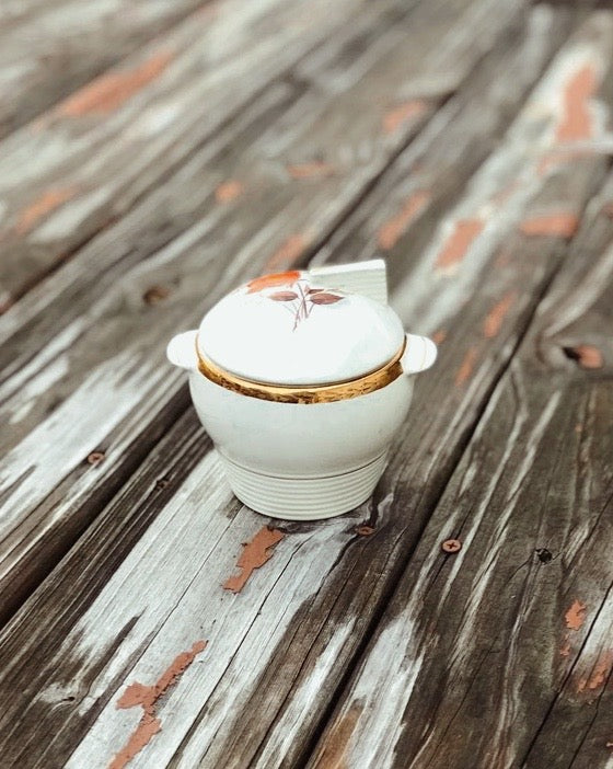White ceramic pot with a lid on a wooden surface