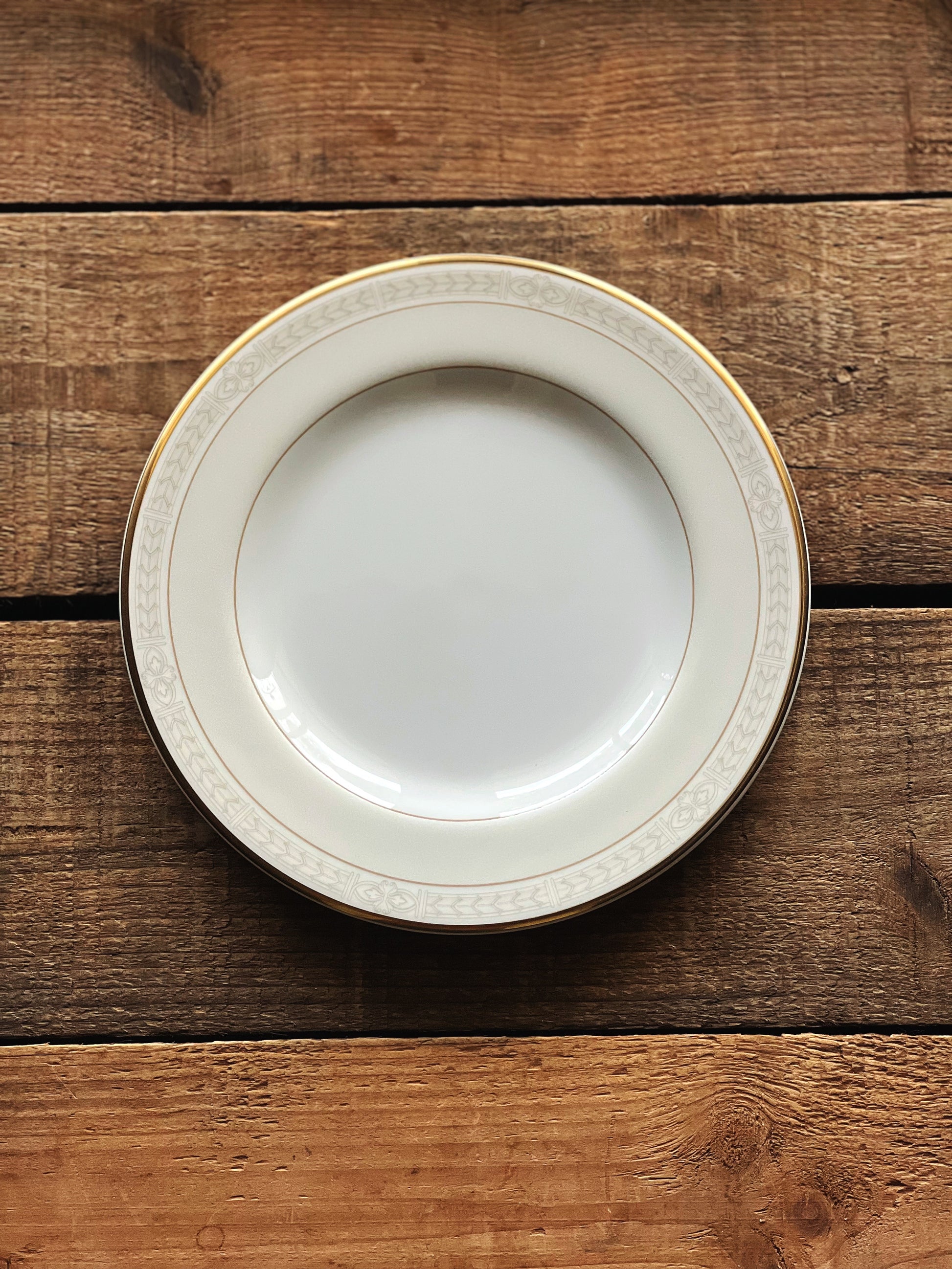 White plate with gold rim on a wooden surface