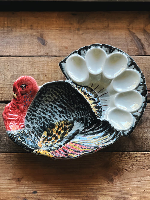 Ceramic dish shaped like a turkey with egg compartments on a wooden surface