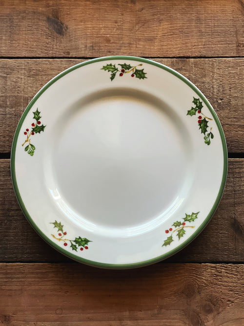 White plate with holly design on a wooden surface