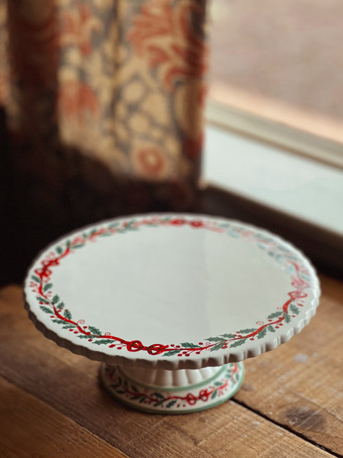 Decorative ceramic cake stand with floral patterns on a wooden surface.
