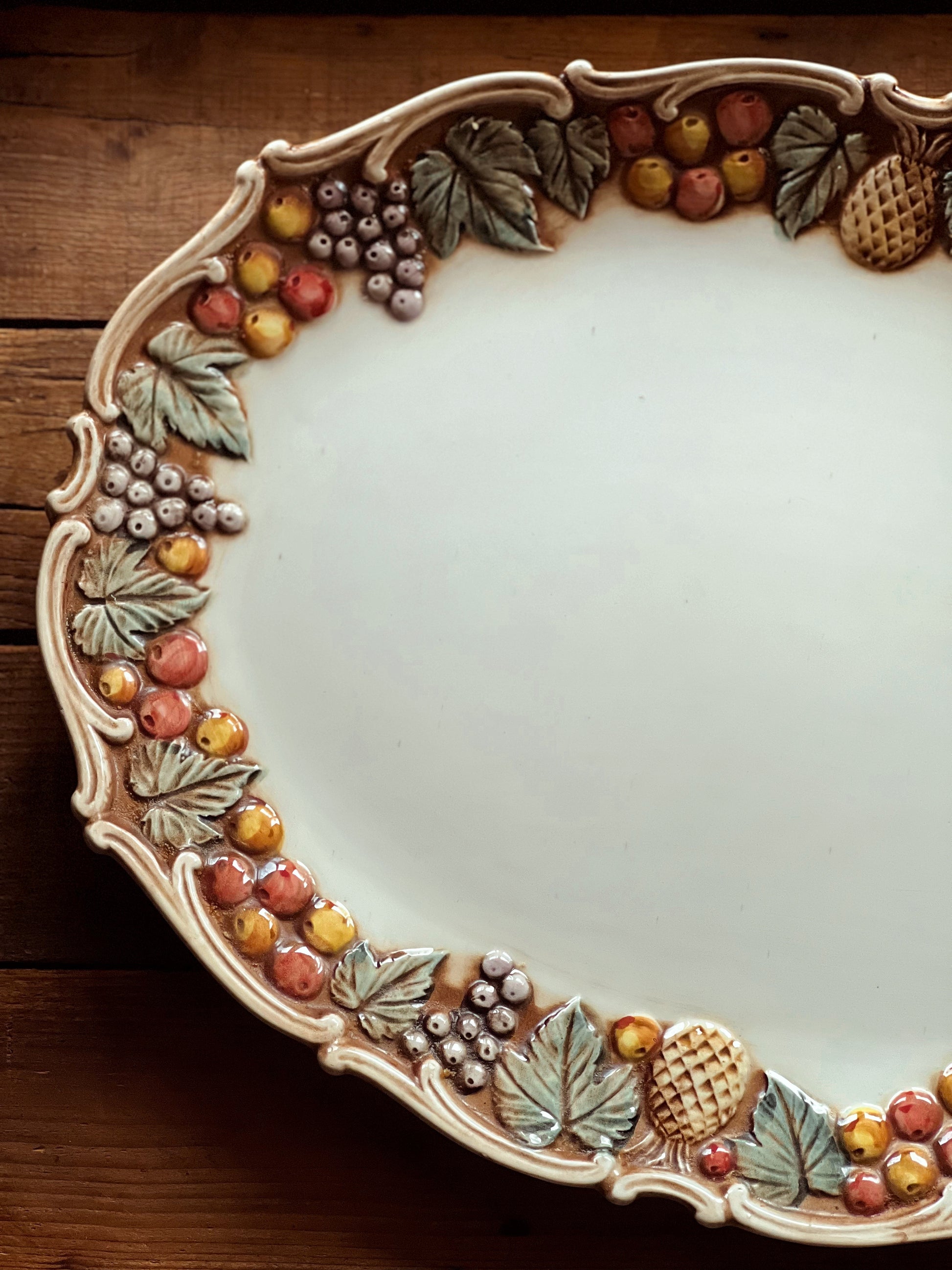 Decorative ceramic plate with fruit and leaf patterns on a wooden surface