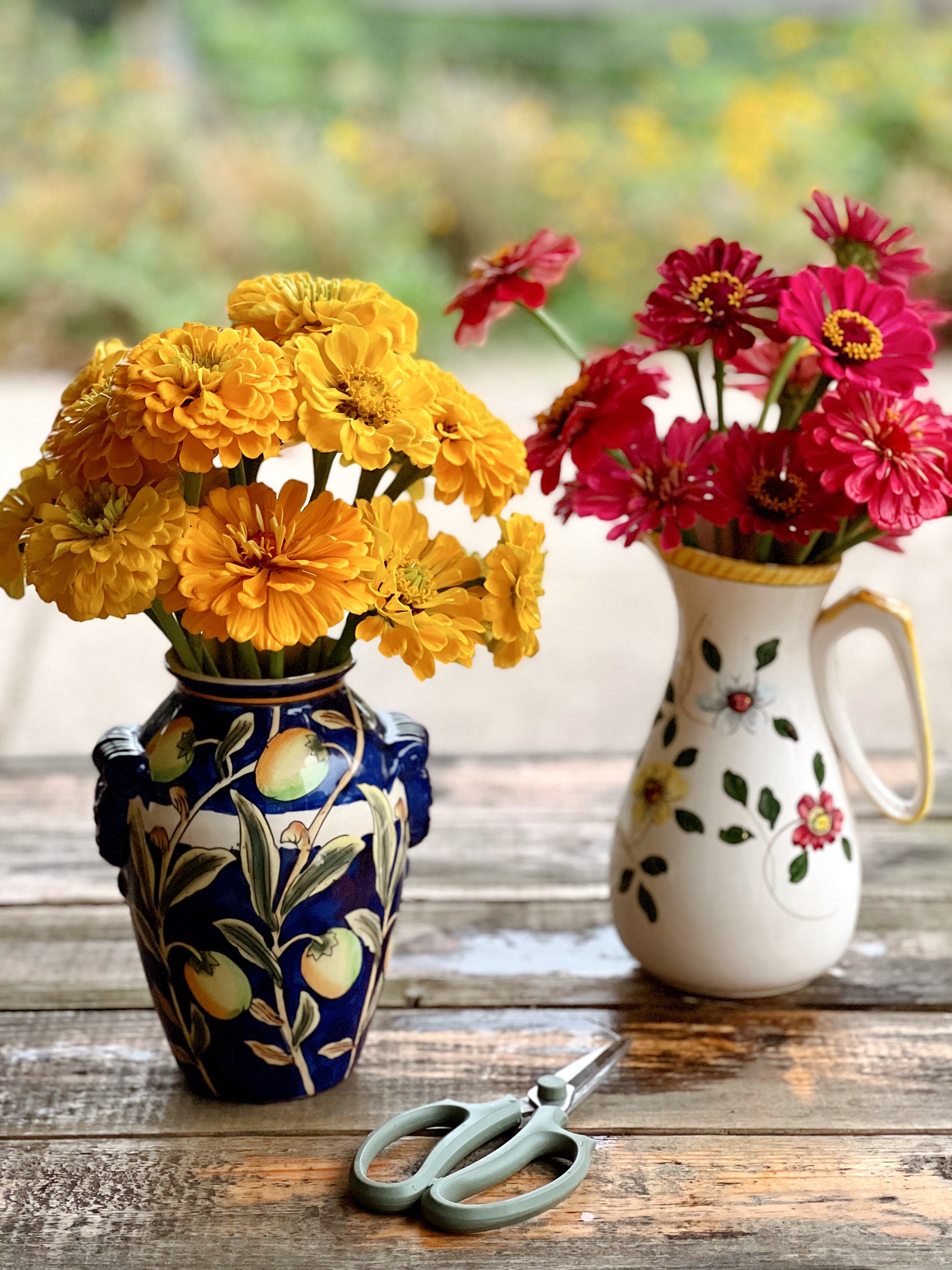 Hand painted white vintage pitcher with multicolored flowers. The pitcher is filled with fresh cut flowers.