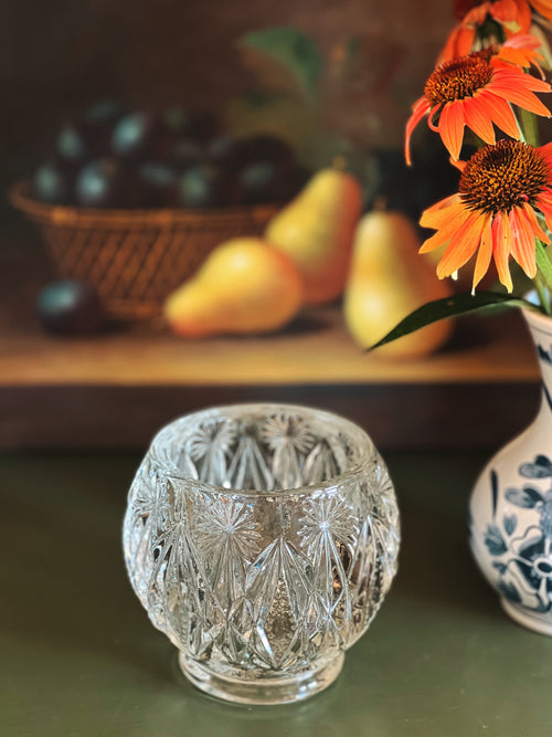 Decorative crystal glass on a table with fruits and flowers in the background