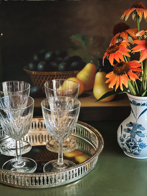 Tray with crystal glasses, fruit, and a vase with flowers on a table.