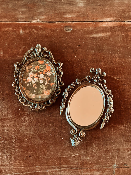 Two ornate mirrors on a wooden surface