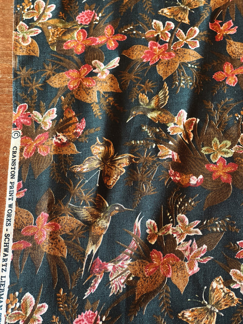 Floral and butterfly pattern on a fabric swatch with a visible brand label.