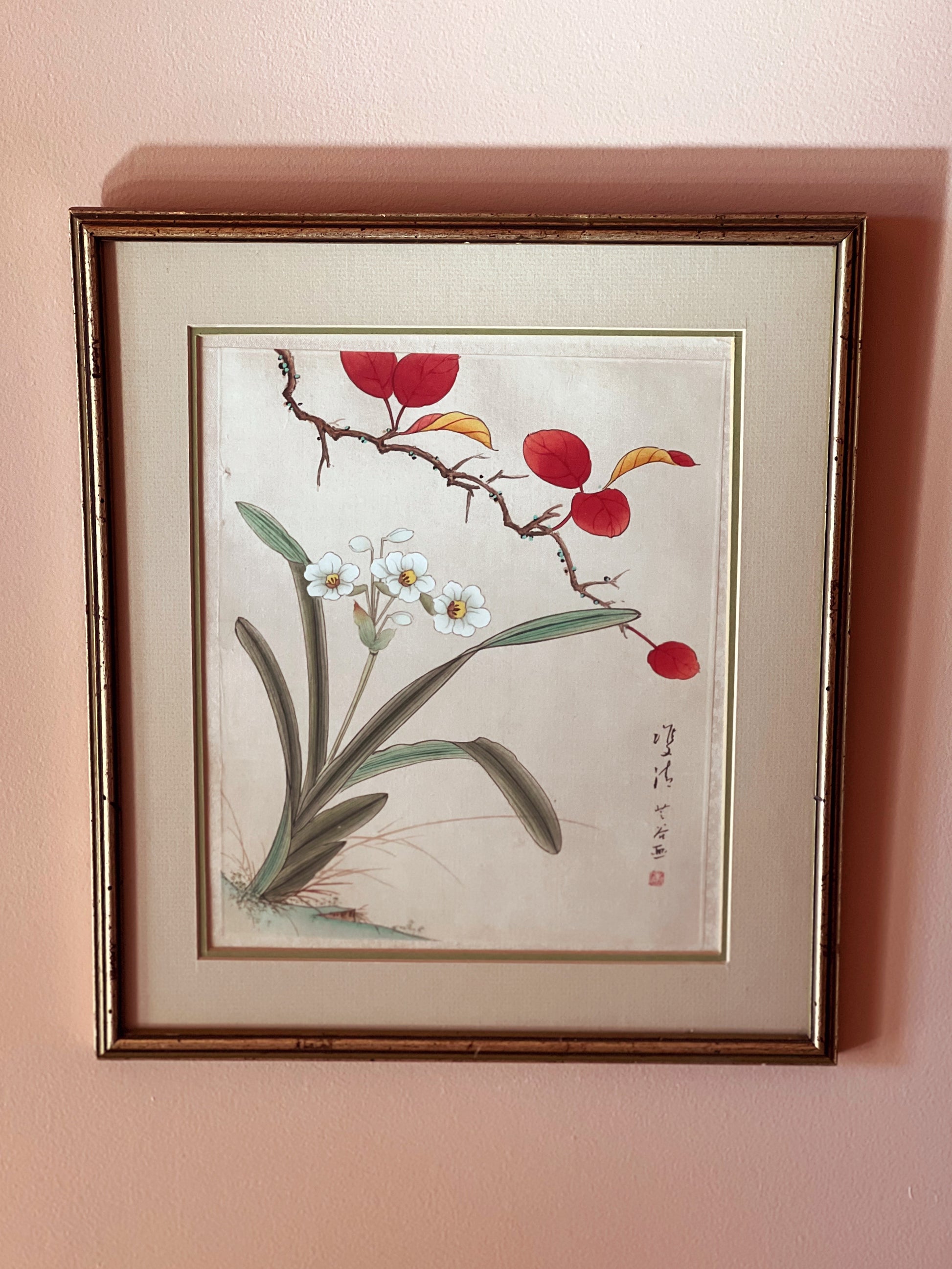 Framed artwork of red berries and white flowers on a pink wall