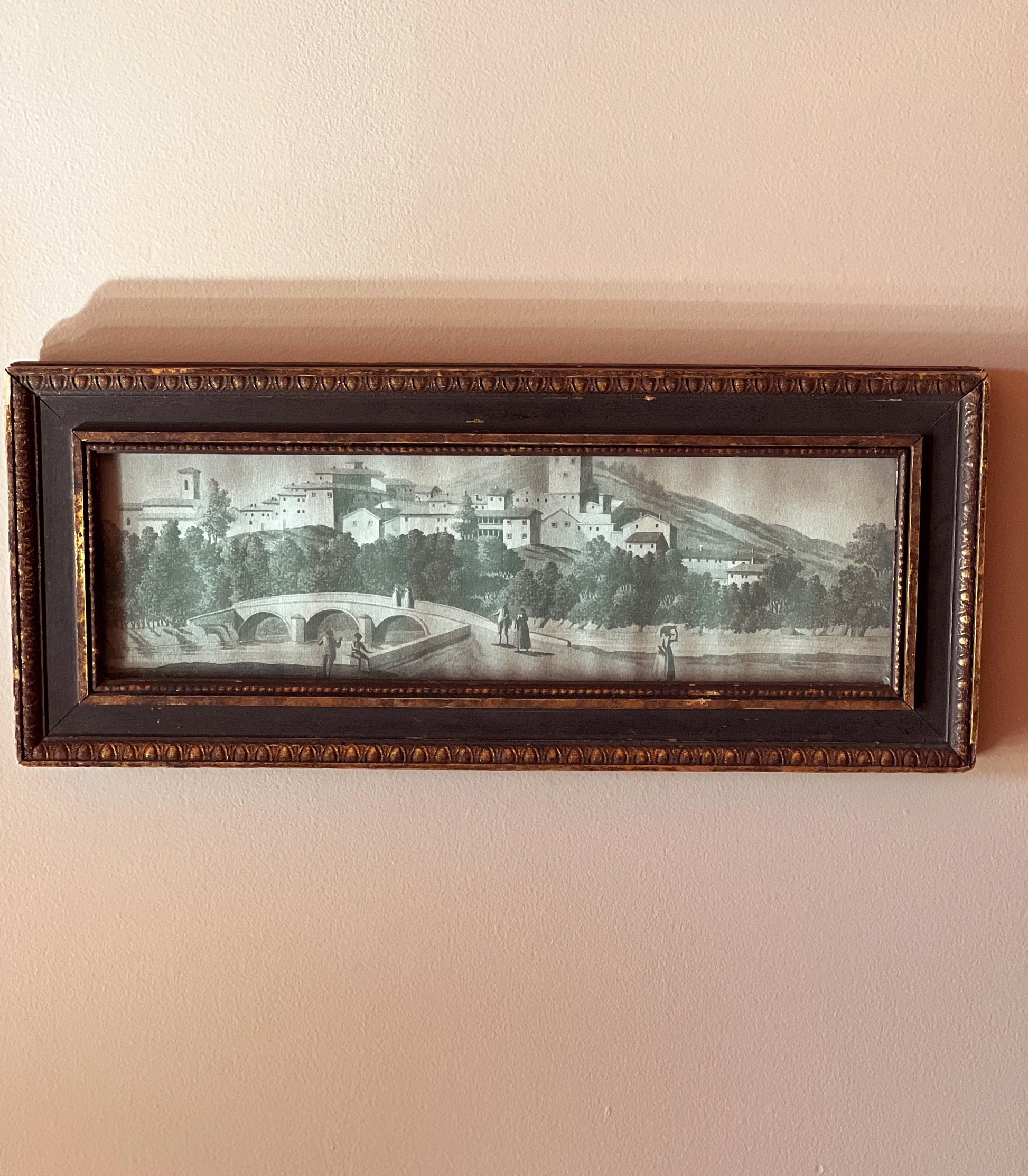 Framed artwork of a scenic landscape on a beige wall
