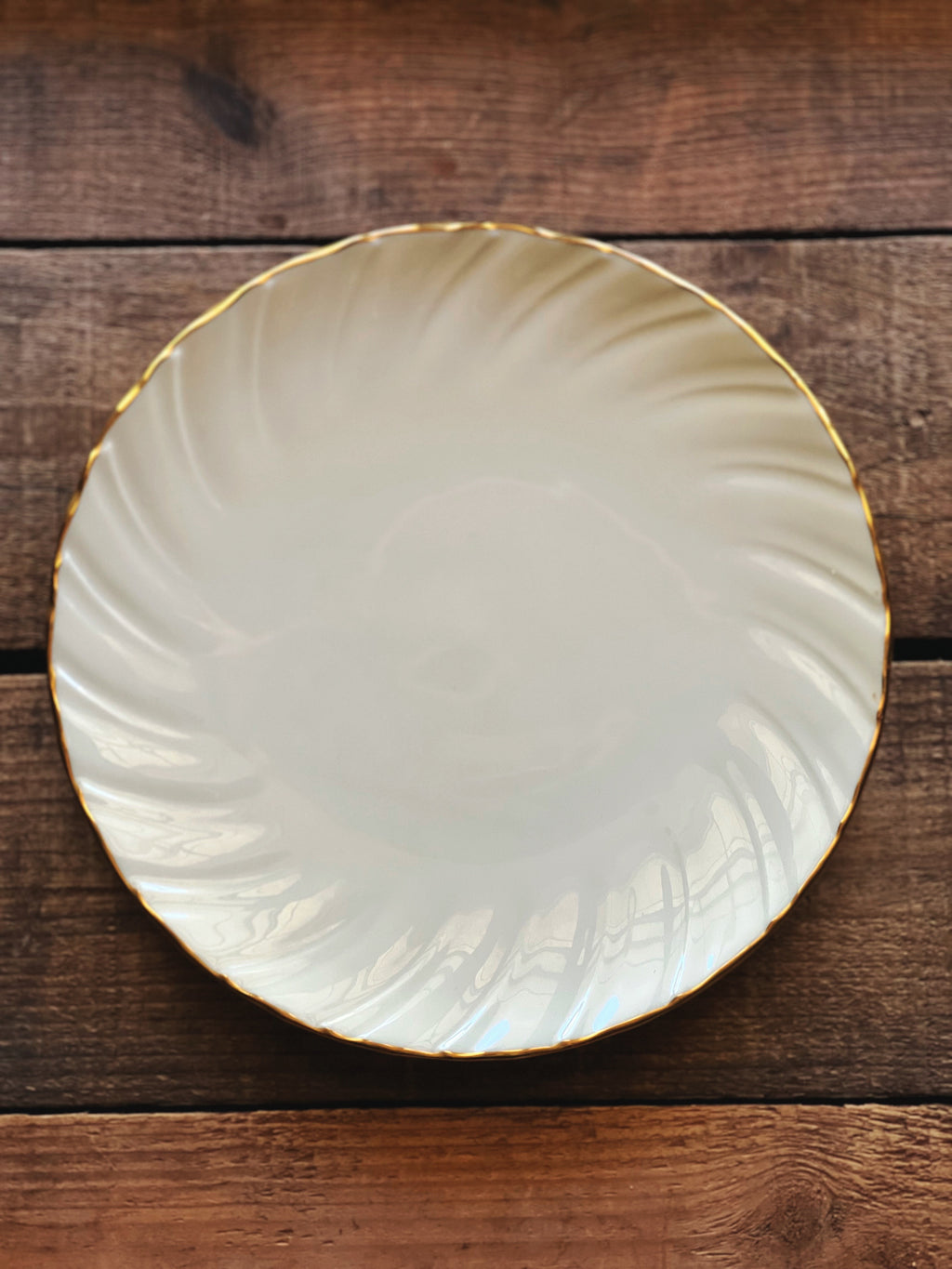 White ceramic plate with gold rim on a wooden surface