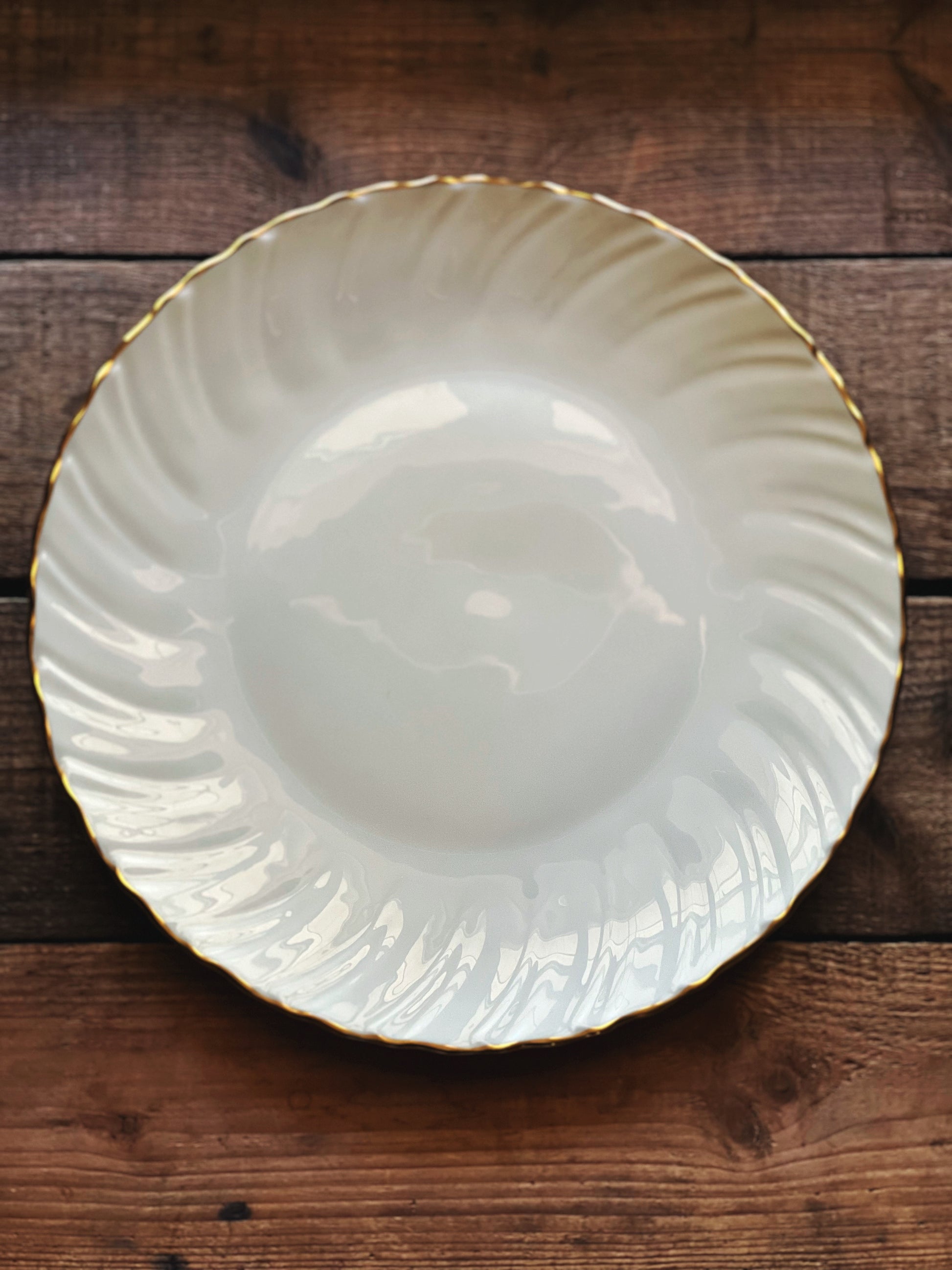 White ceramic plate with gold rim on a wooden surface