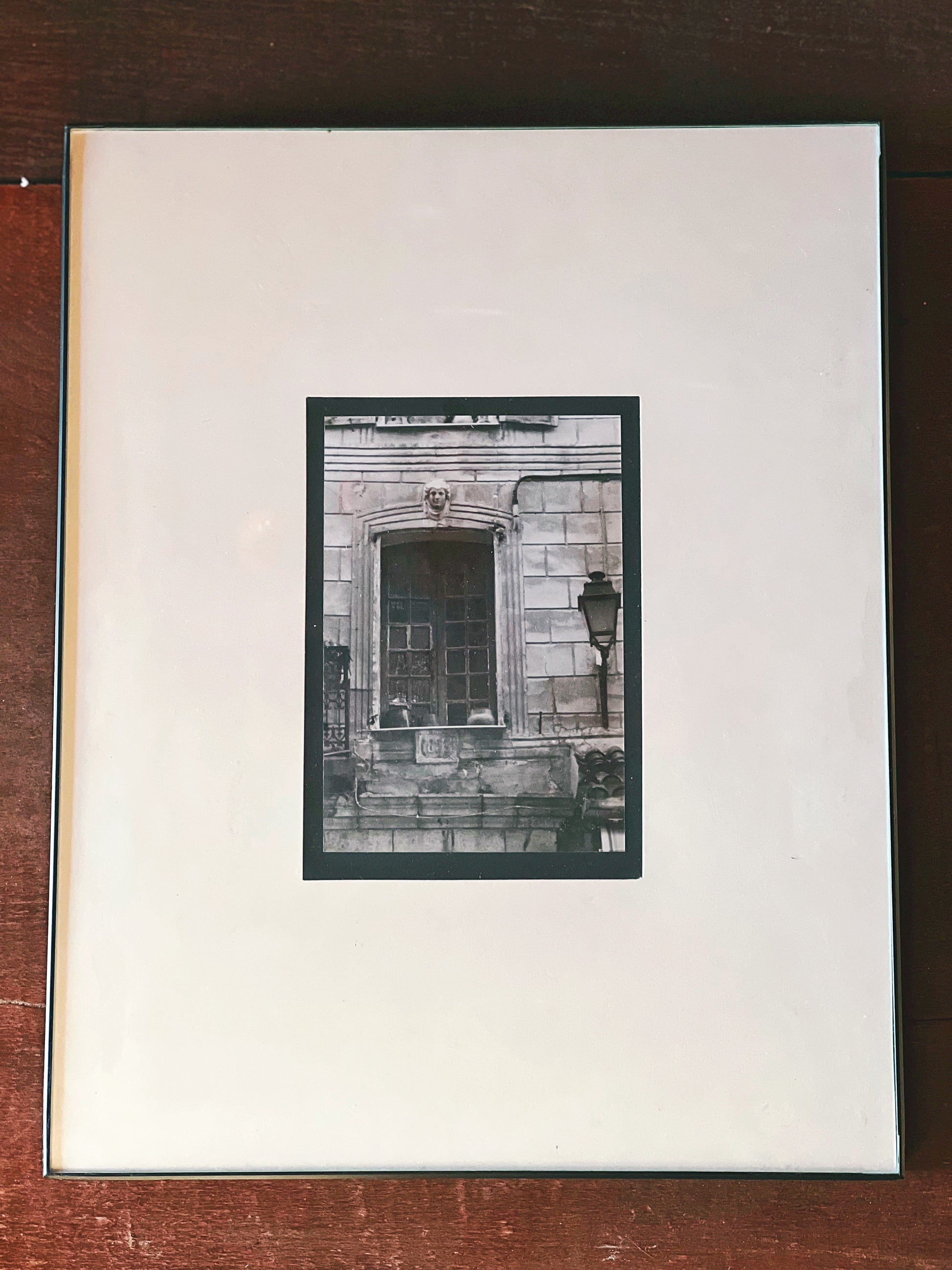 Framed black and white photograph of a building facade on a wooden surface