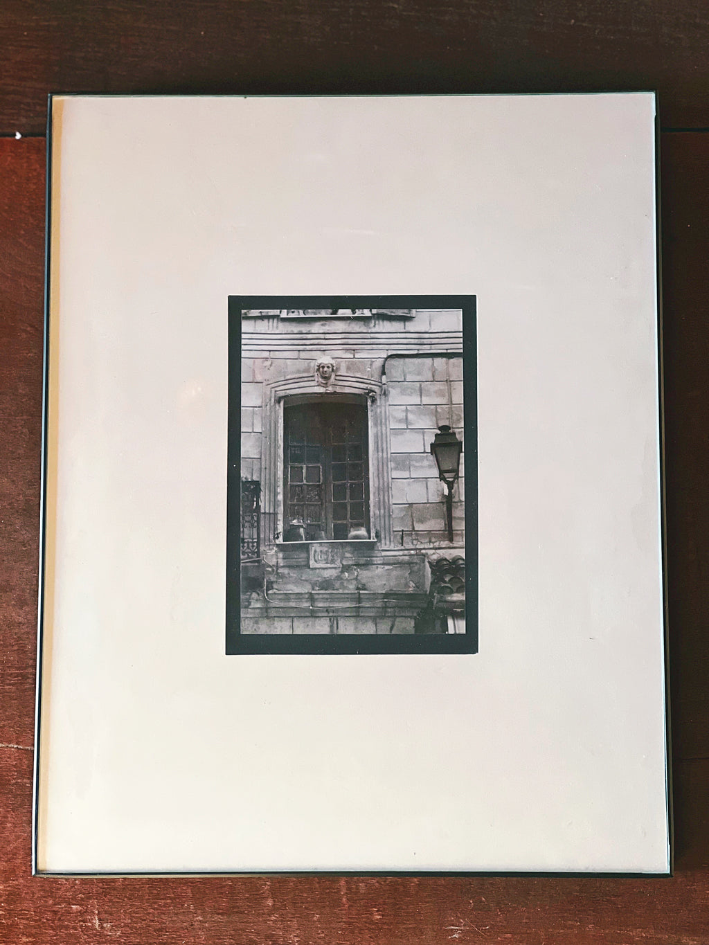 Framed black and white photograph of a building facade on a wooden surface