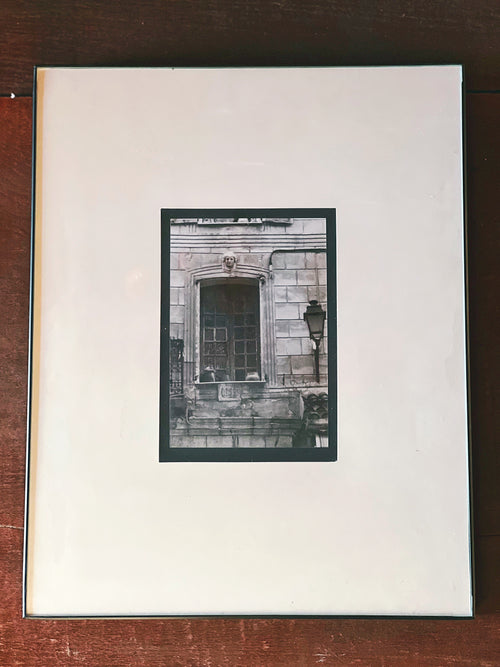 Framed black and white photograph of a building facade on a wooden surface