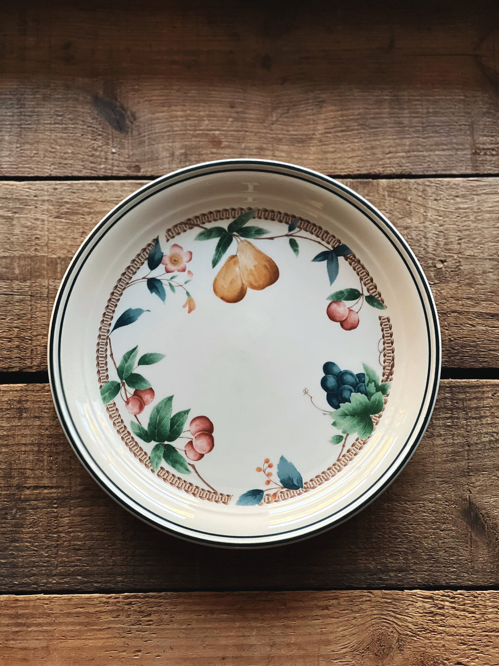 Decorative ceramic plate with fruit design on a wooden surface