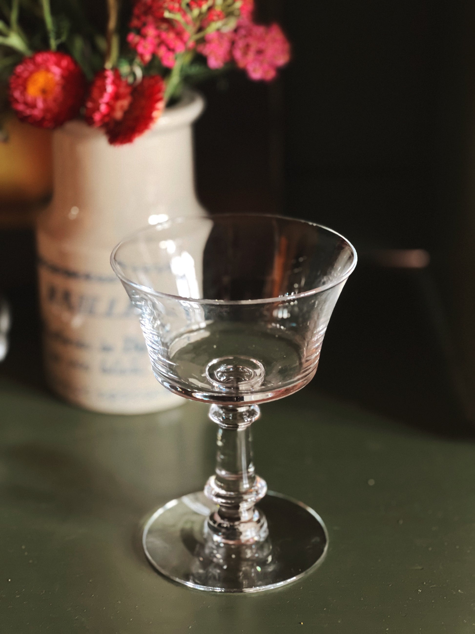 Clear glass goblet on a dark surface with a blurred background