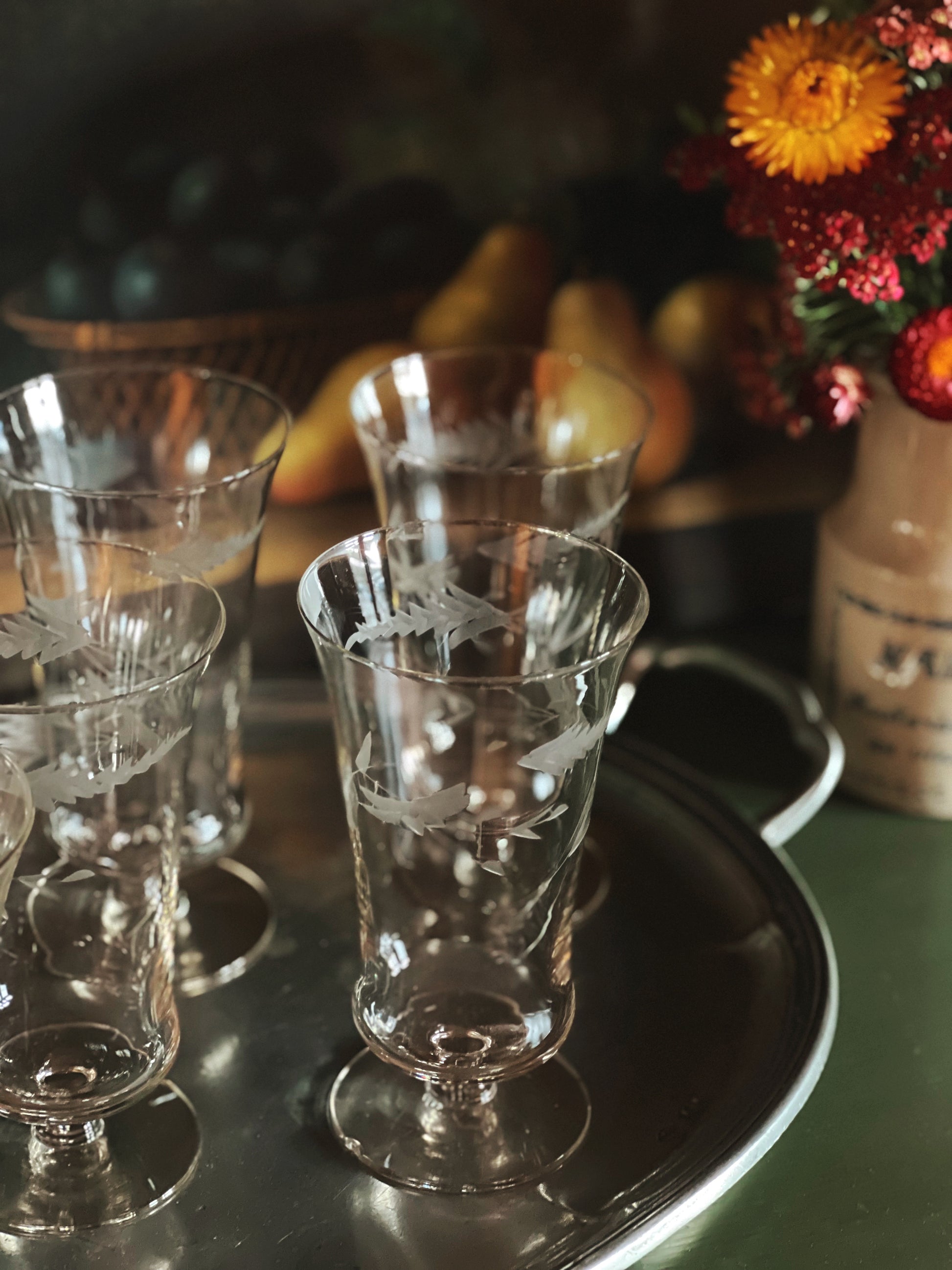 Set of etched glass tumblers on a tray with a blurred background