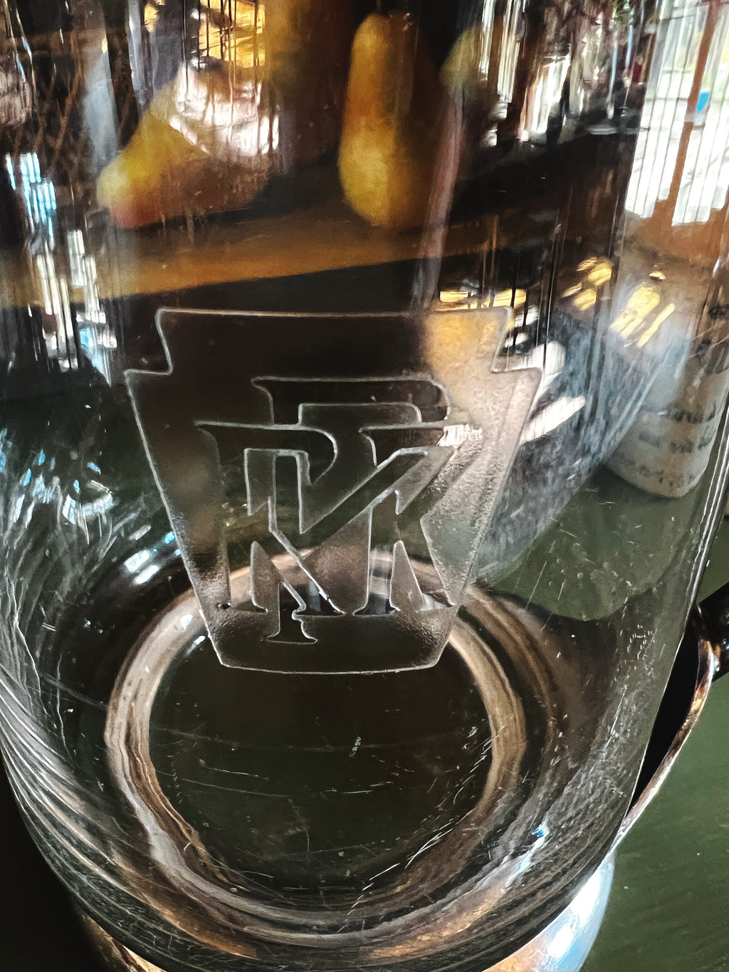 Close-up of a glass with an engraved logo, possibly 'FK', on a blurred background.