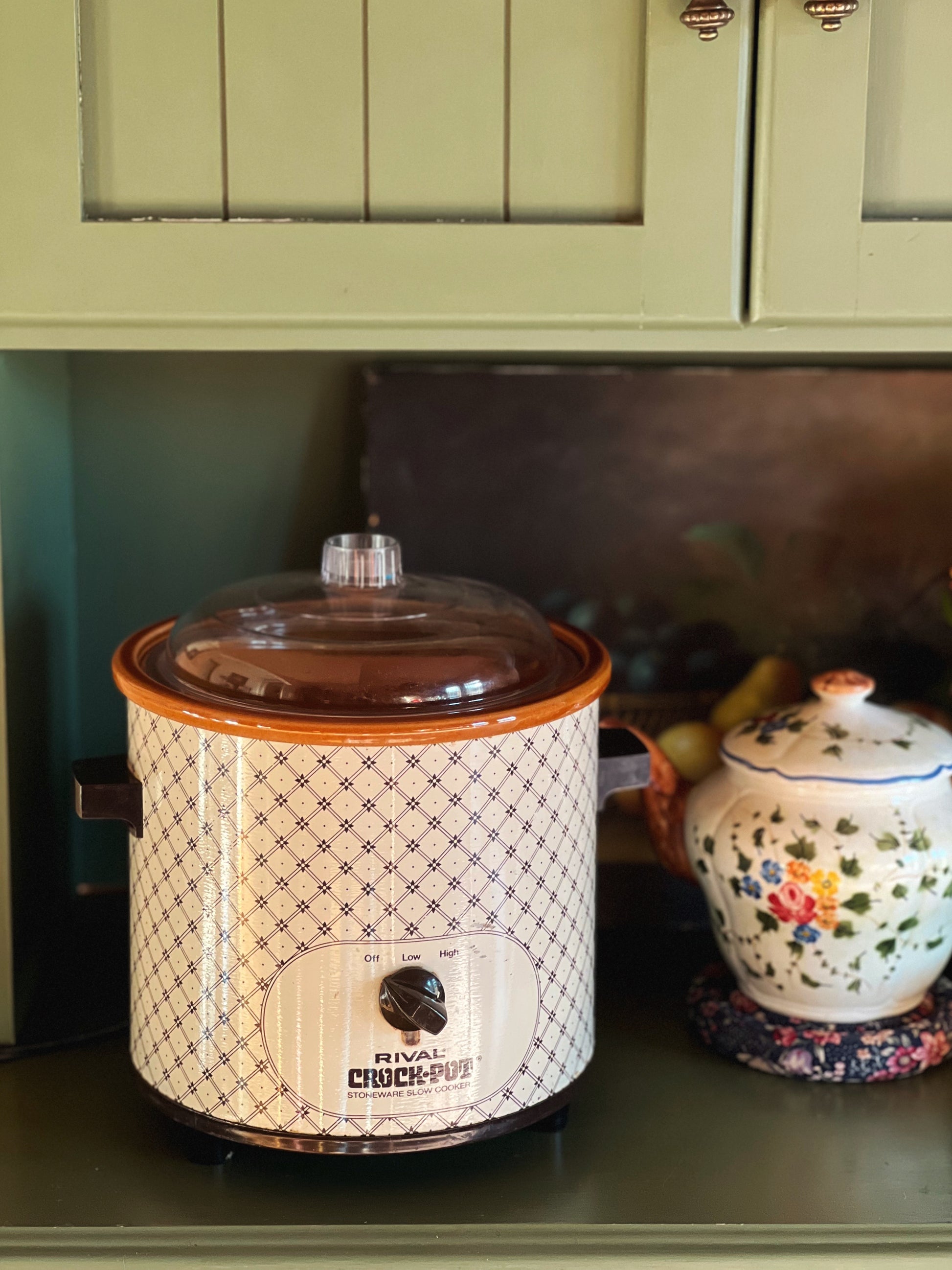 Crock pot on a kitchen counter with green cabinets in the background
