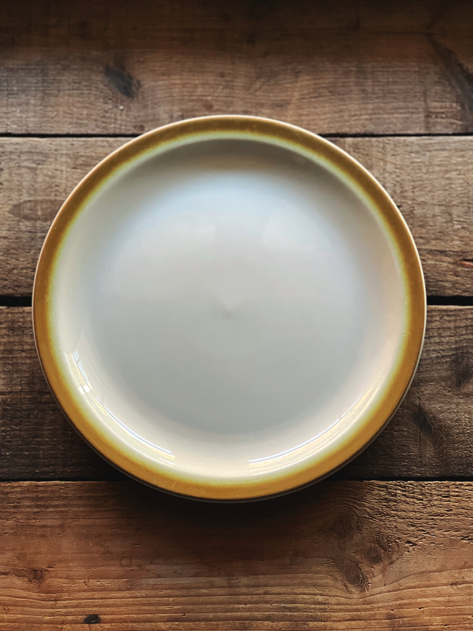 White ceramic plate with a yellow rim on a wooden surface