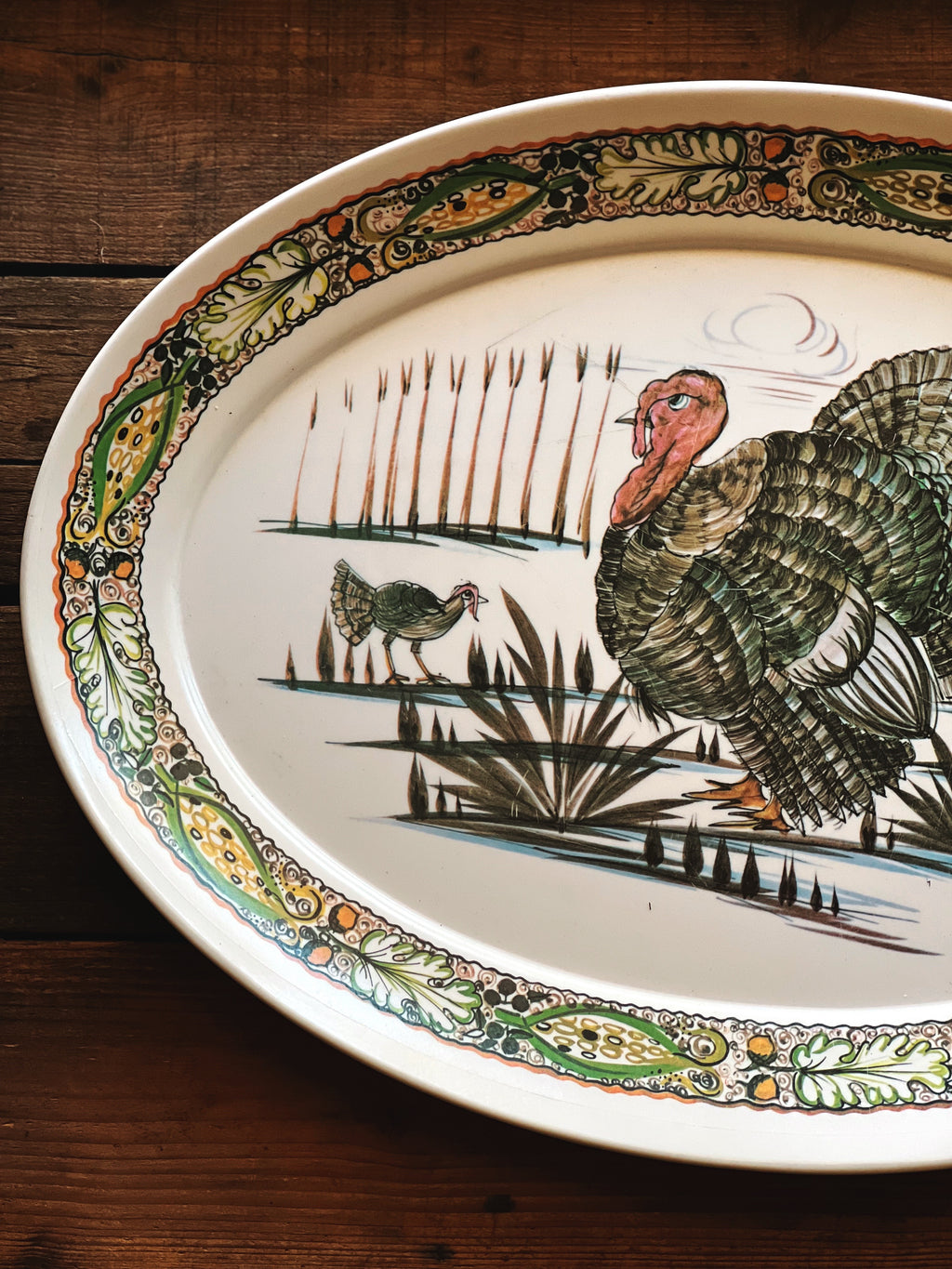 Decorative plate with a turkey and chicken design on a wooden surface
