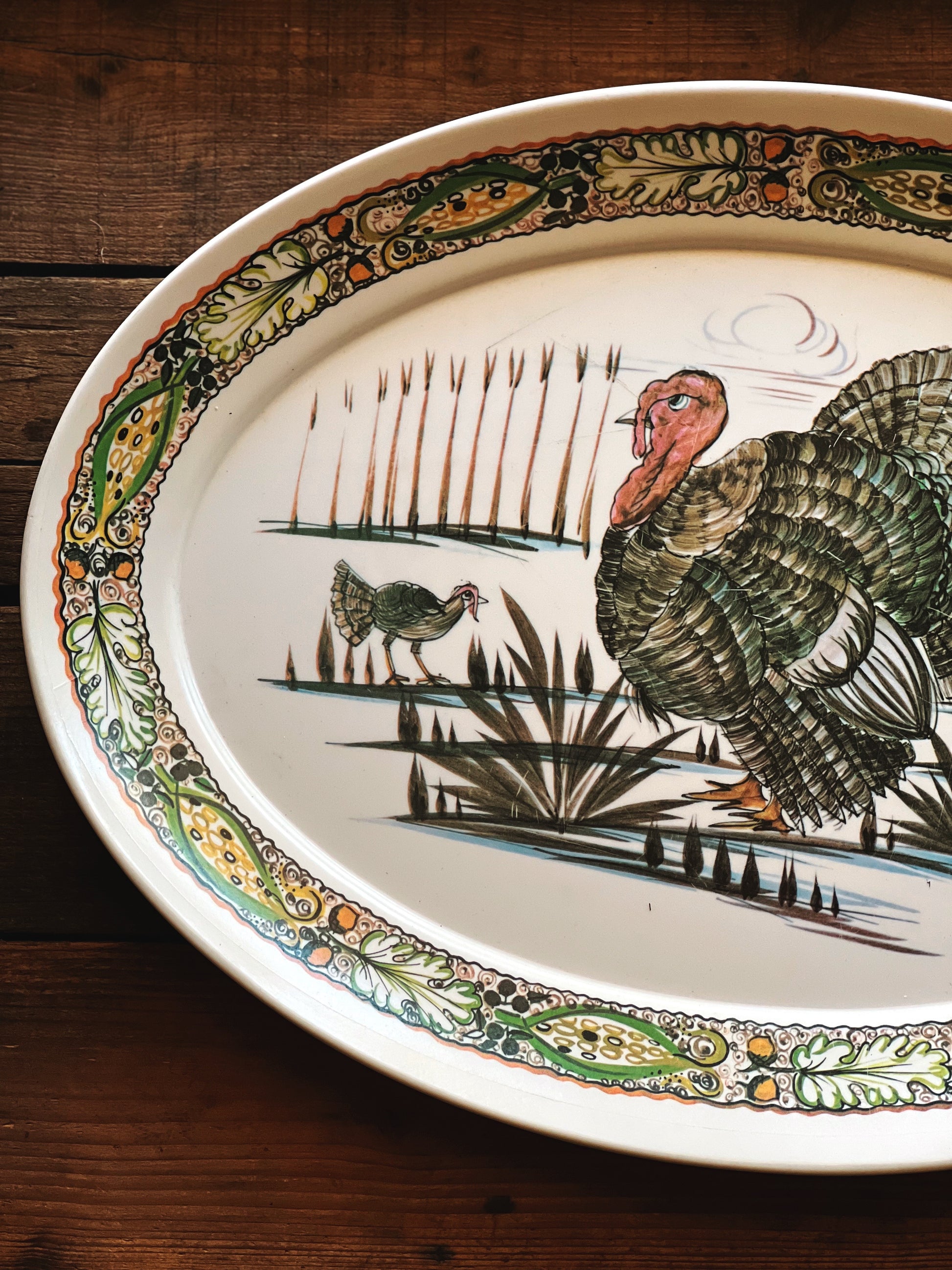 Decorative plate with a turkey and chicken design on a wooden surface