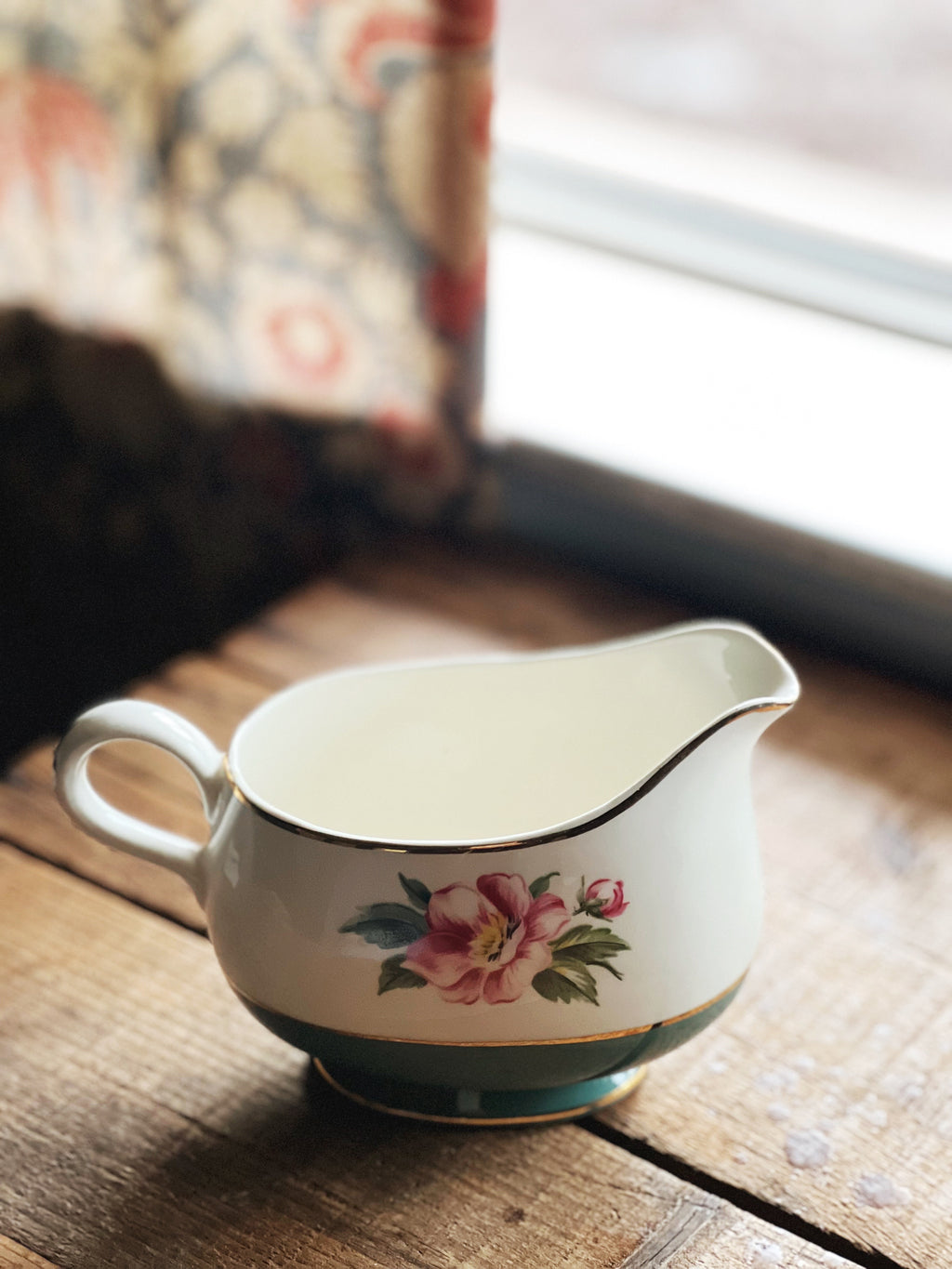 Decorative ceramic pitcher with floral design on a wooden surface