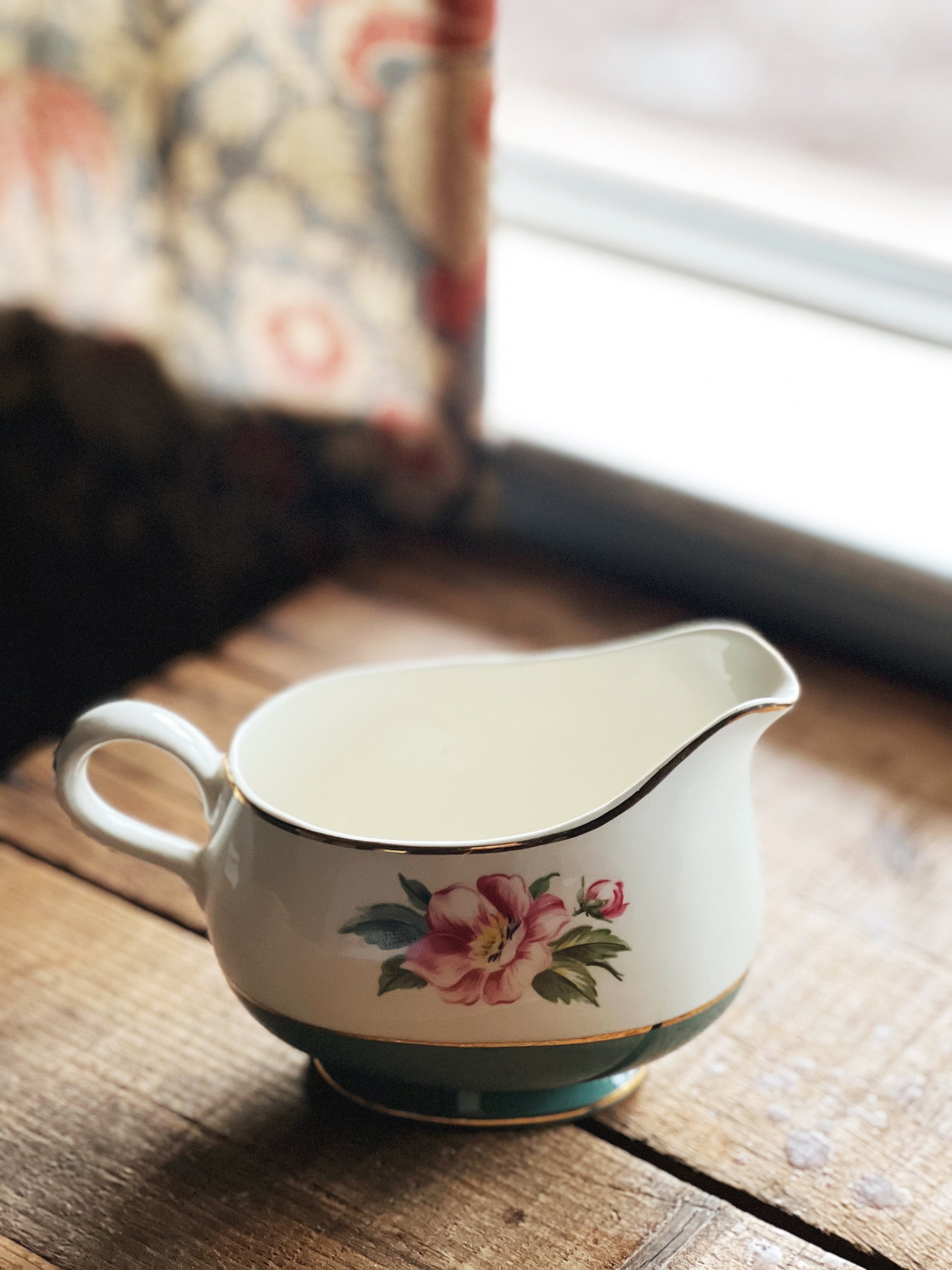 Decorative ceramic pitcher with floral design on a wooden surface