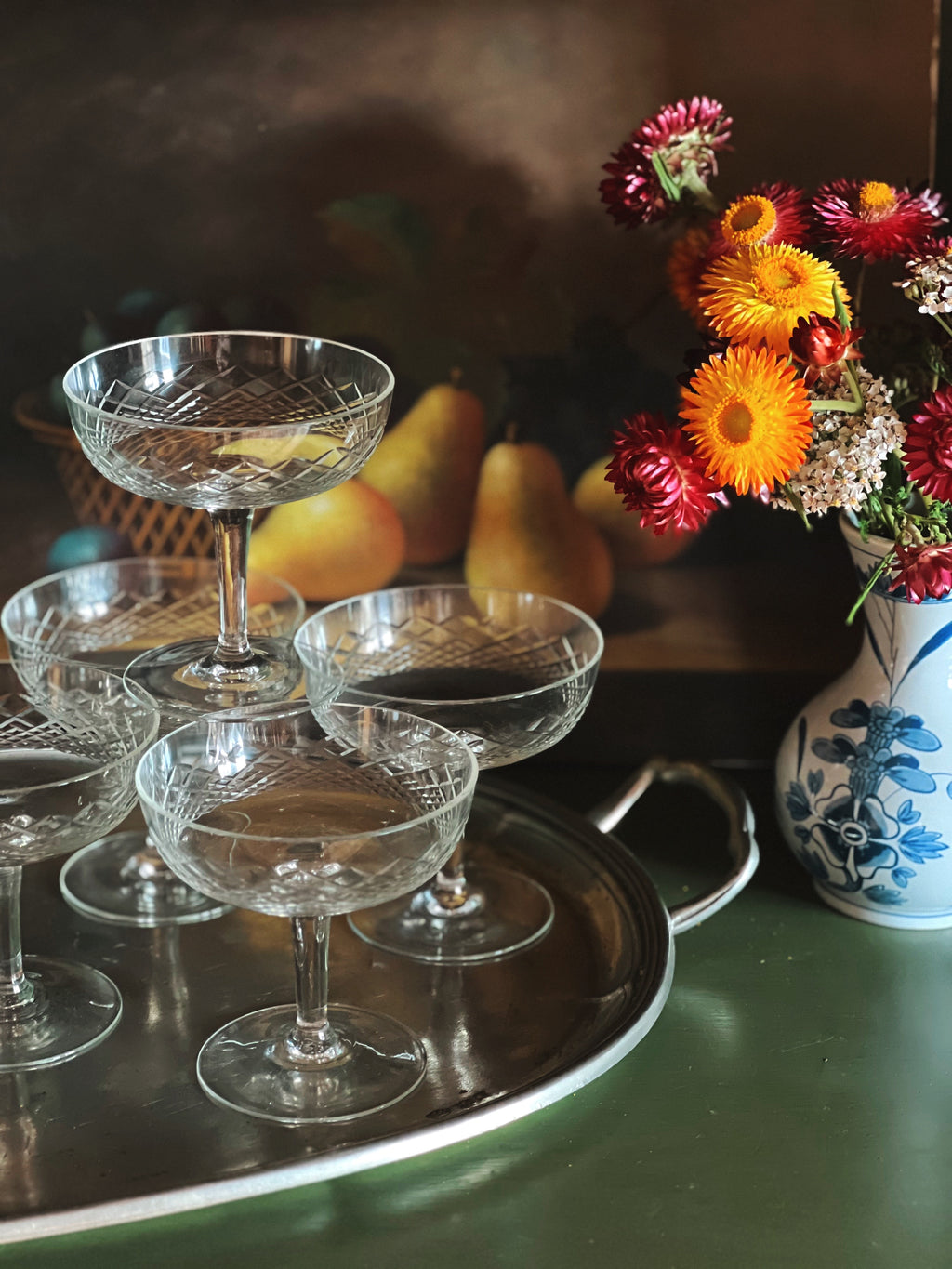 Set of crystal glasses on a tray with pears and flowers in the background