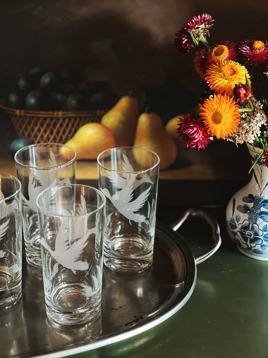 Set of etched glass tumblers on a tray with pears and flowers in the background