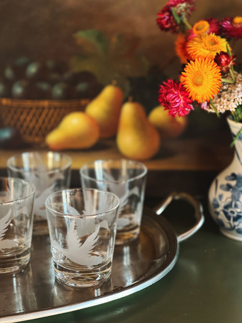 Set of etched glass tumblers on a tray with fruit and flowers in the background
