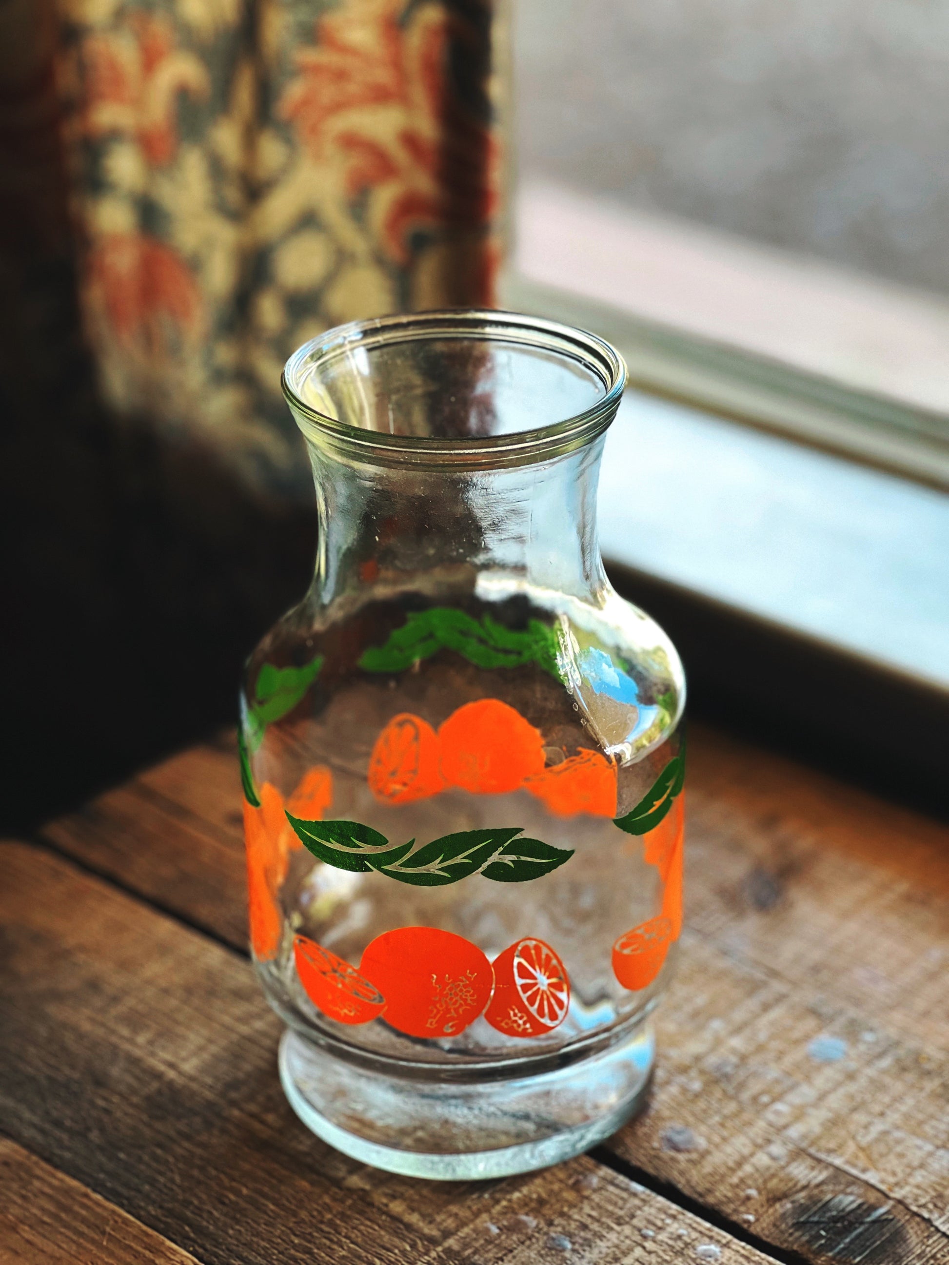 Clear glass vase with fruit design on a wooden surface