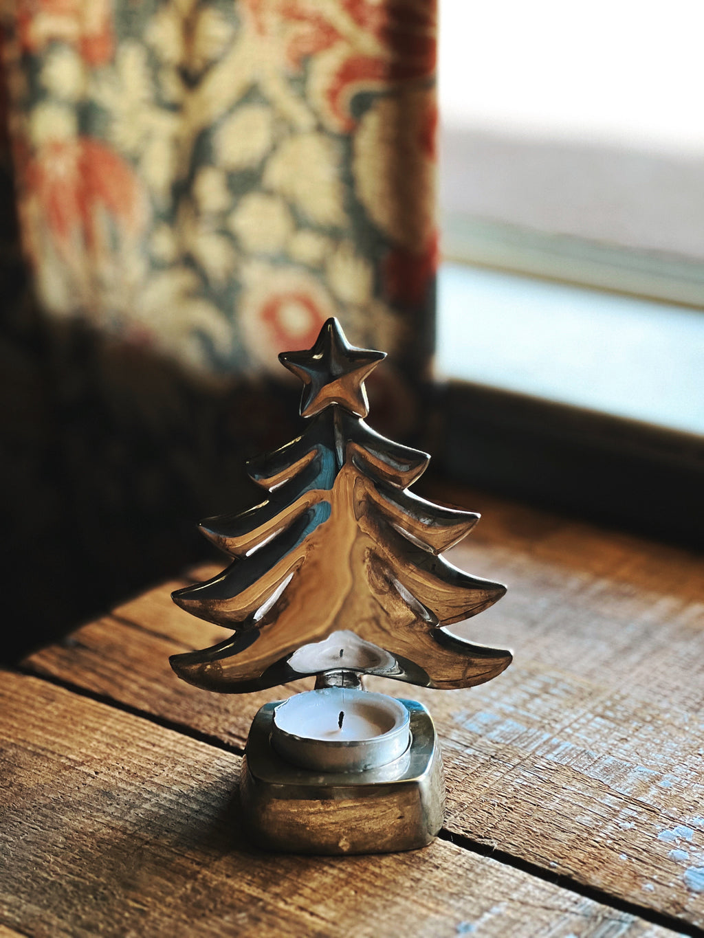 Decorative metal Christmas tree candle holder on a wooden surface