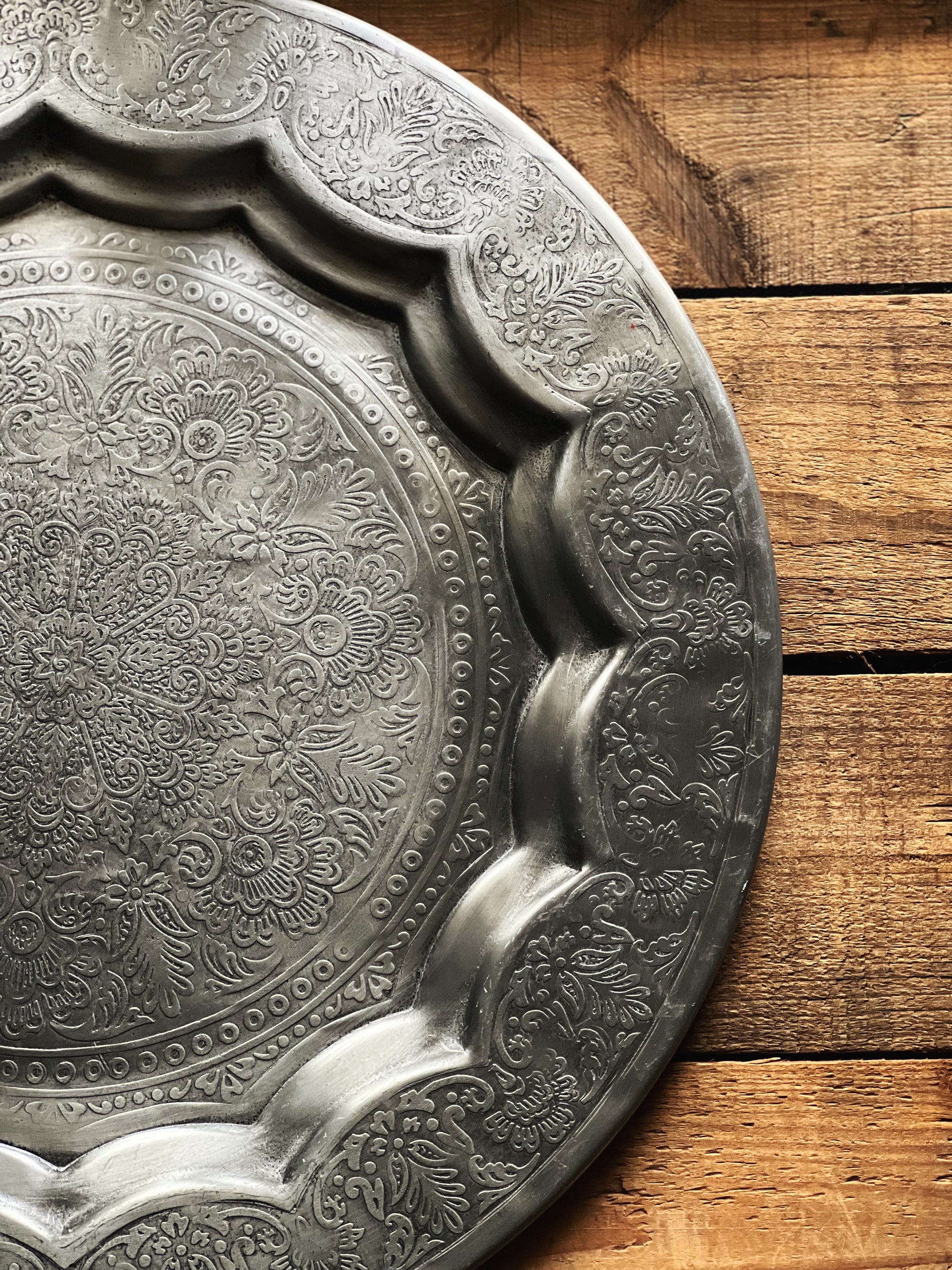 Decorative metal tray with intricate patterns on a wooden surface