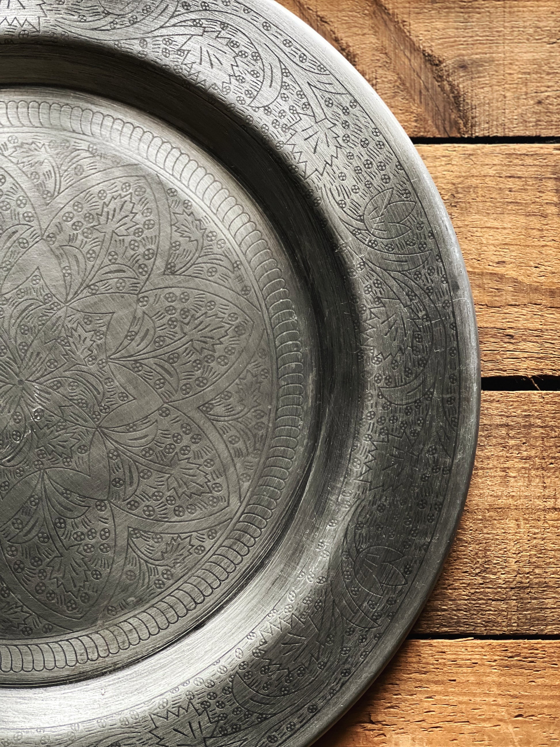 Decorative metal tray with intricate patterns on a wooden surface
